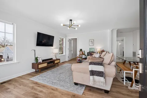 a living room with furniture a flat screen tv and kitchen view