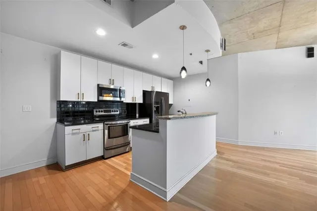 a kitchen with kitchen island sink stove and white cabinets with wooden floor