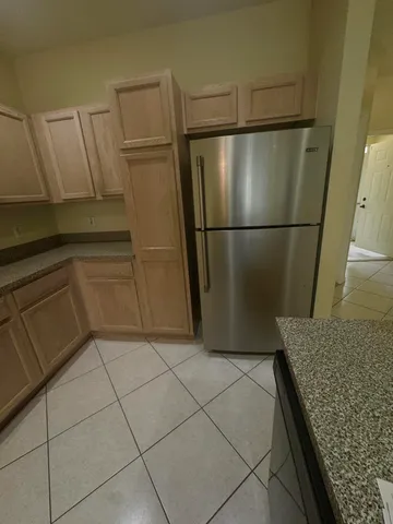 a view of a refrigerator in kitchen and an empty room