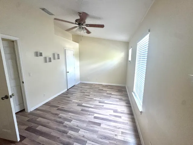 a view of a hallway with a hardwood floor and a ceiling fan