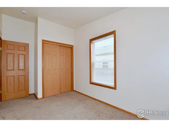 a view of an empty room with closet and a window