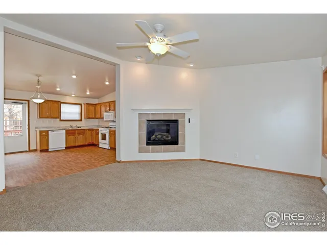 a view of an empty room with a ceiling fan and kitchen view