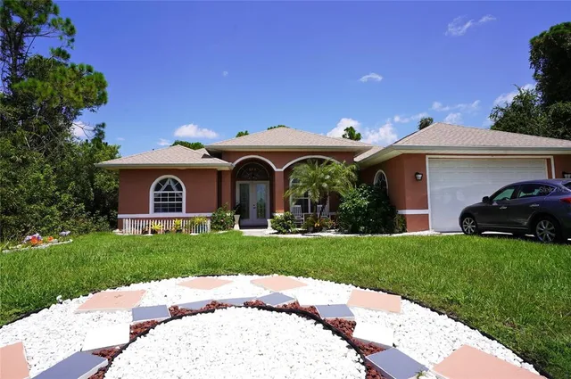 a view of a white house with a small yard and a large tree