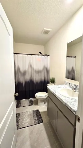 a bathroom with a granite countertop sink a toilet a mirror and shower