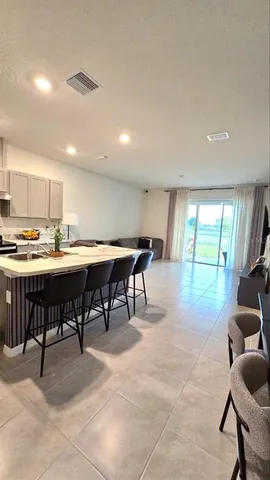 a open dining room with stainless steel appliances kitchen island granite countertop a table and chairs in it