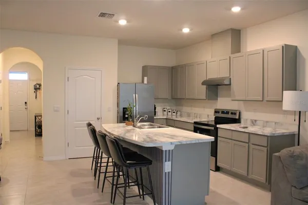 a kitchen with stainless steel appliances granite countertop a table chairs sink refrigerator and cabinets