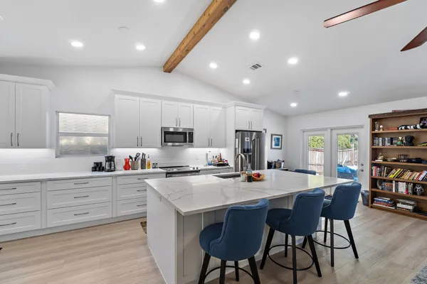 a open dining room with stainless steel appliances a dining table and chairs