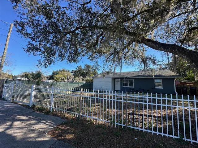 a view of a house with a small yard and a large tree