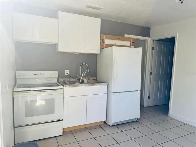 a white refrigerator freezer and a stove sitting inside of a kitchen