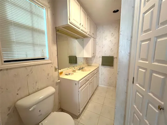 a bathroom with a granite countertop sink a toilet and a window