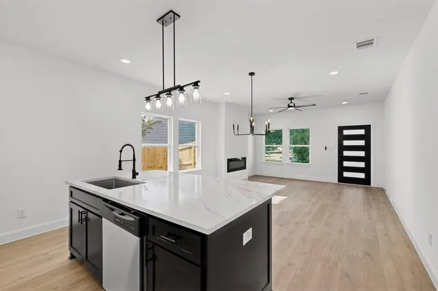 a kitchen with stainless steel appliances granite countertop a sink a stove and a wooden floors