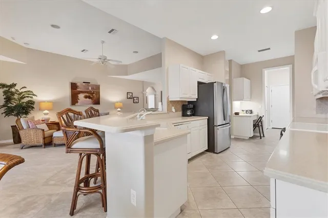 a kitchen that has a lot of white cabinets a sink and a refrigerator