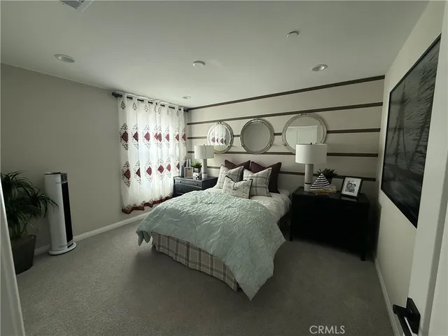 a bed sitting in a bedroom next to a window and a chair