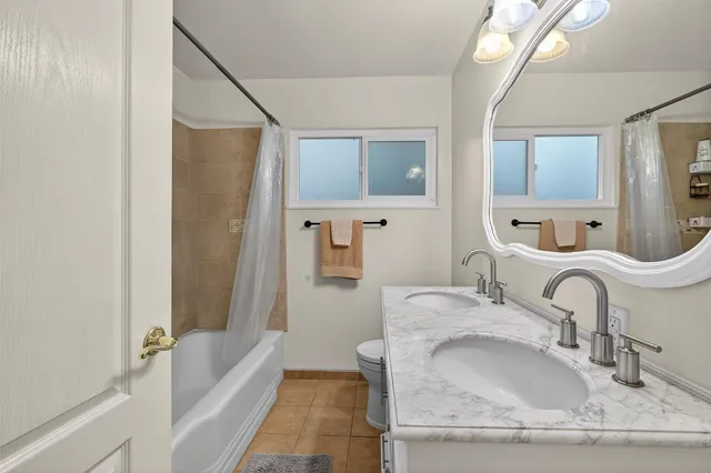 a bathroom with a granite countertop tub sink and mirror