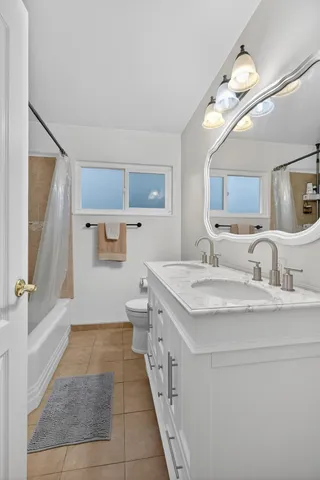 a spacious bathroom with a granite countertop sink a toilet a mirror and shower