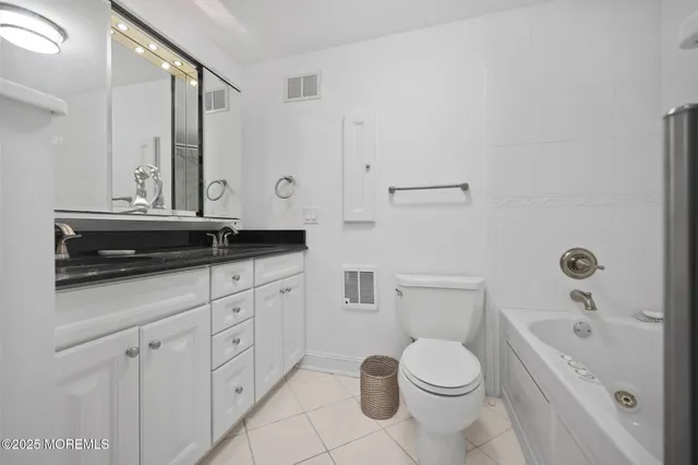 a bathroom with a granite countertop toilet sink and mirror