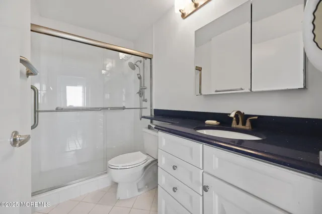 a bathroom with a granite countertop sink a toilet and a shower