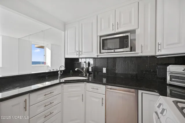 a kitchen with granite countertop white cabinets and a sink