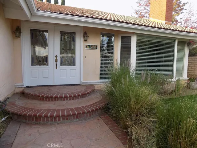 a view of a house with potted plants and a bench