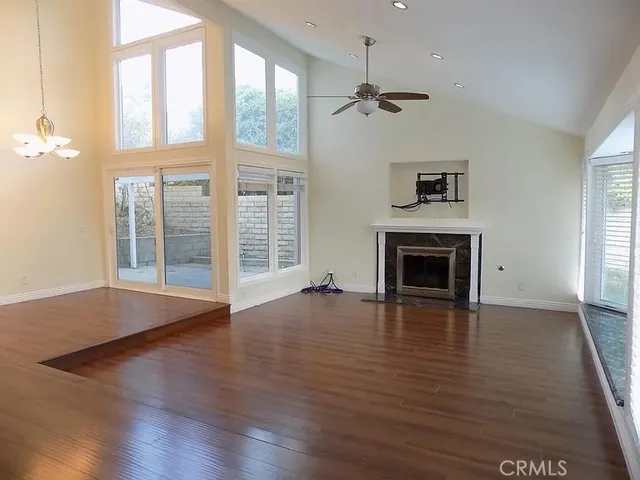 an empty room with wooden floor fireplace and windows