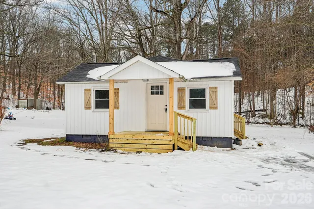 a view of a blue house with snow on the road