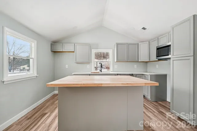 a kitchen with stainless steel appliances a sink a stove a refrigerator cabinets and a window