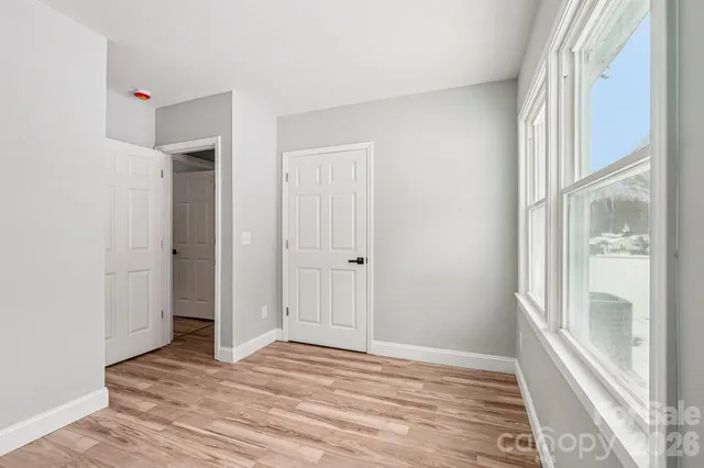 a view of an empty room with wooden floor and a window