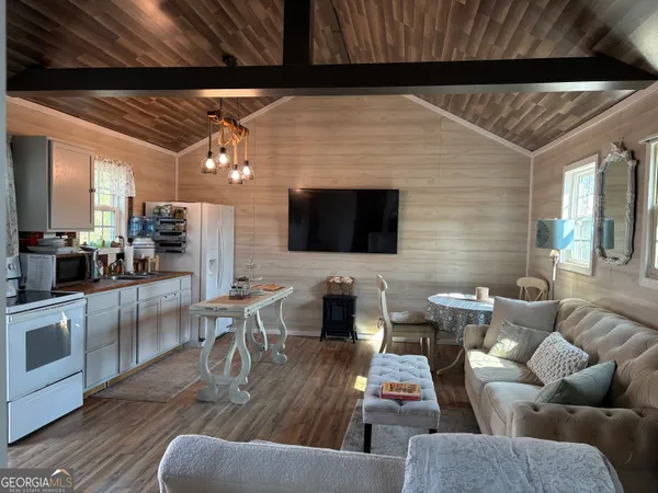 a living room with furniture a flat screen tv and kitchen view