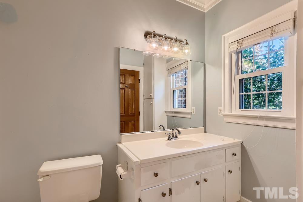 7301 Sandy Grove Court Raleigh, NC 27615 - Photo 17 of 28 a bathroom with a toilet a sink a mirror and a window