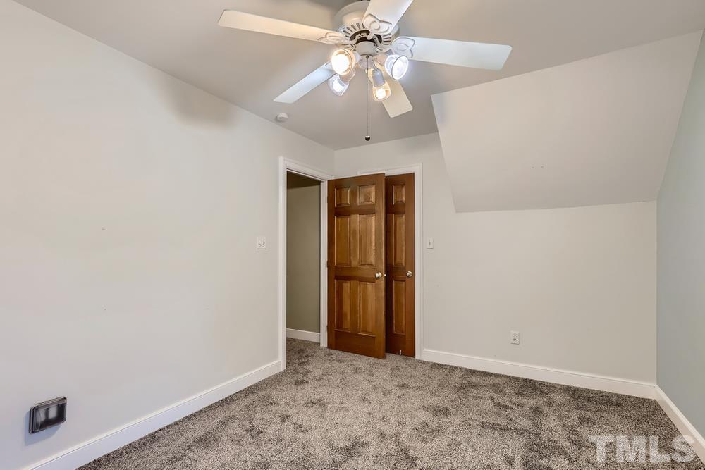 7301 Sandy Grove Court Raleigh, NC 27615 - Photo 23 of 28 an empty room with a ceiling fan and carpet