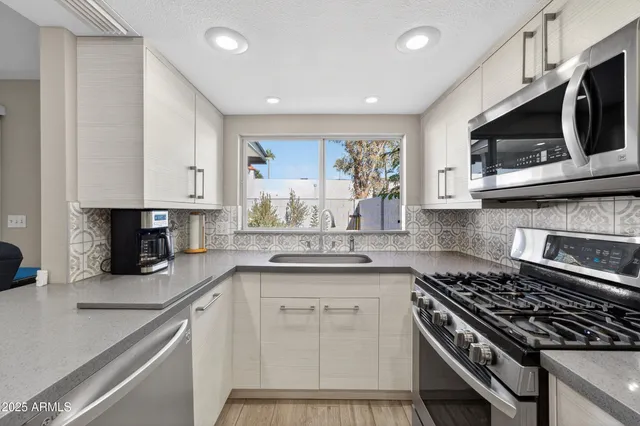 a kitchen with stainless steel appliances white cabinets and stove top oven