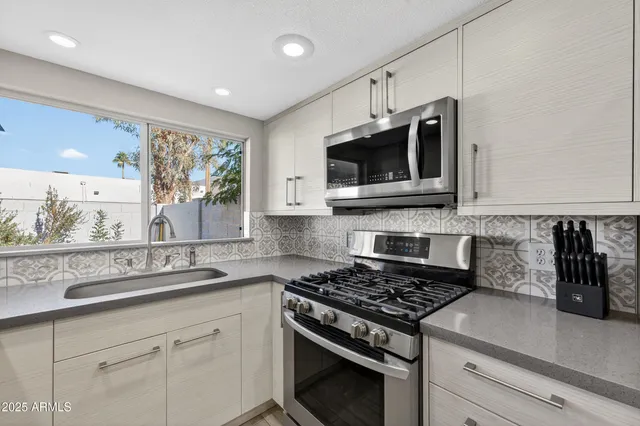 a kitchen with stainless steel appliances granite countertop white cabinets granite counter tops and a window