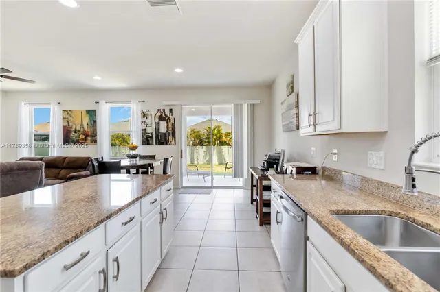 a large kitchen with granite countertop a sink a counter top space appliances and cabinets