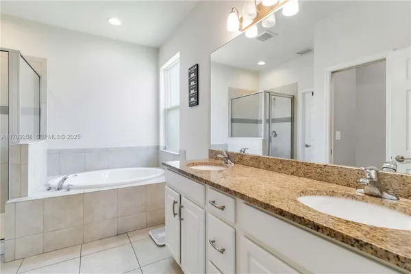 a bathroom with a granite countertop bathtub sink double and mirror