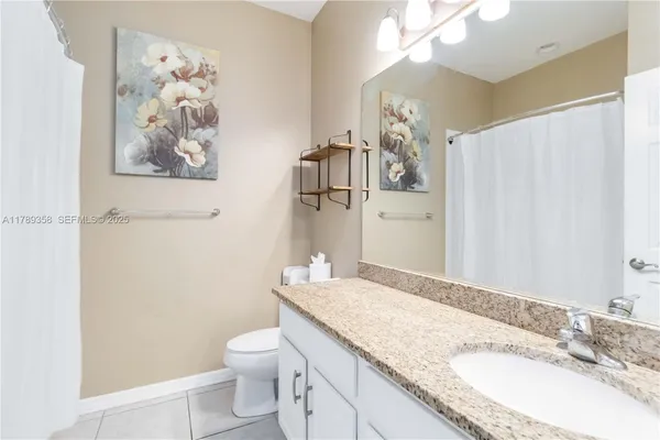 a bathroom with a granite countertop sink a toilet and a mirror