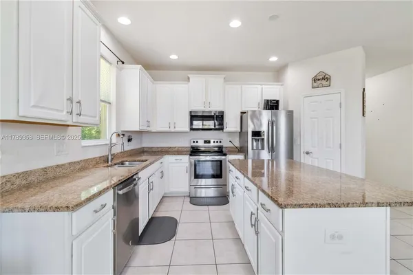a kitchen with granite countertop a sink a counter top space stainless steel appliances and cabinets