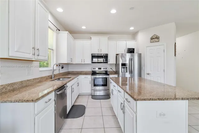 a kitchen with granite countertop a sink a counter top space stainless steel appliances and cabinets