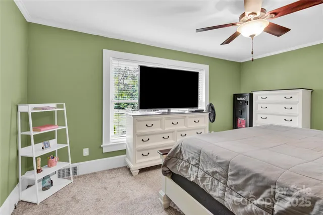 a bedroom with a bed and a flat tv screen on dresser