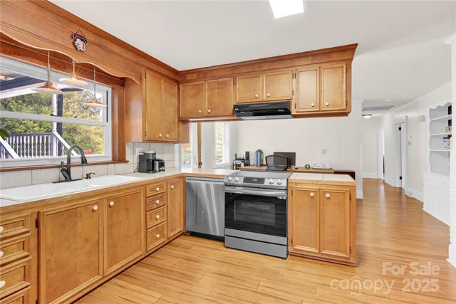 a kitchen with stainless steel appliances granite countertop a sink and cabinets with wooden floor