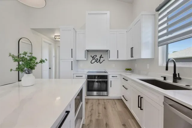 a kitchen with stainless steel appliances granite countertop a white cabinets a sink a stove and a window