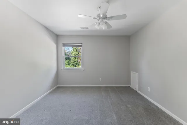 an empty room with windows and fan