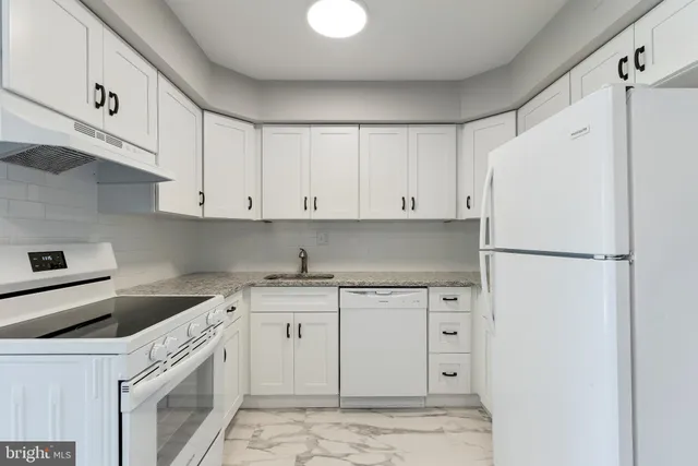 a kitchen with granite countertop a white cabinets and white appliances