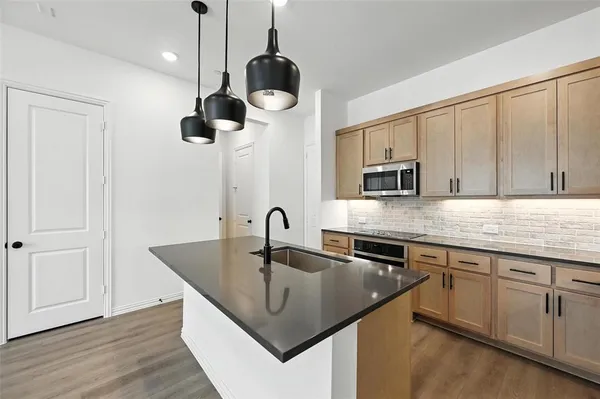 a kitchen with stainless steel appliances granite countertop a sink a microwave and wooden cabinets