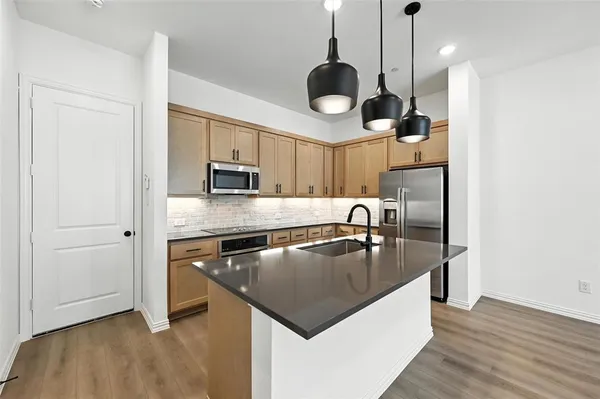 a kitchen with stainless steel appliances granite countertop a sink a microwave and wooden floors