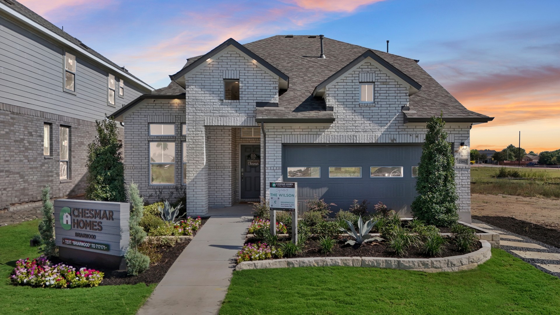 A striking modern home with brick siding and well-maintained landscaping at dusk.