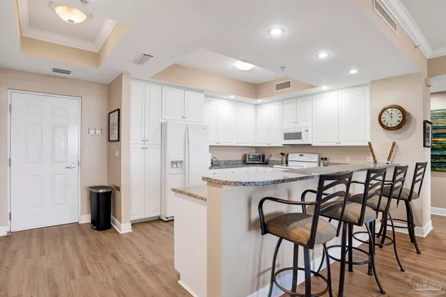 a kitchen with granite countertop a table chairs stove a refrigerator and cabinets