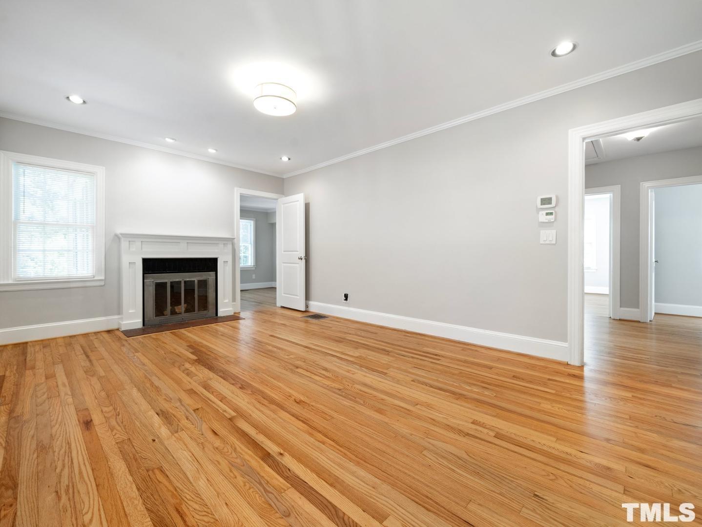 214 Faircloth Street Raleigh, NC 27607 - Photo 11 of 21 an empty room with wooden floor fireplace and windows