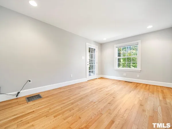 an empty room with wooden floor cabinet and windows
