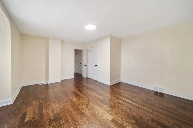 a view of an empty room with wooden floor and closet