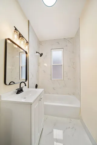 a bathroom with a bathtub sink vanity and mirror